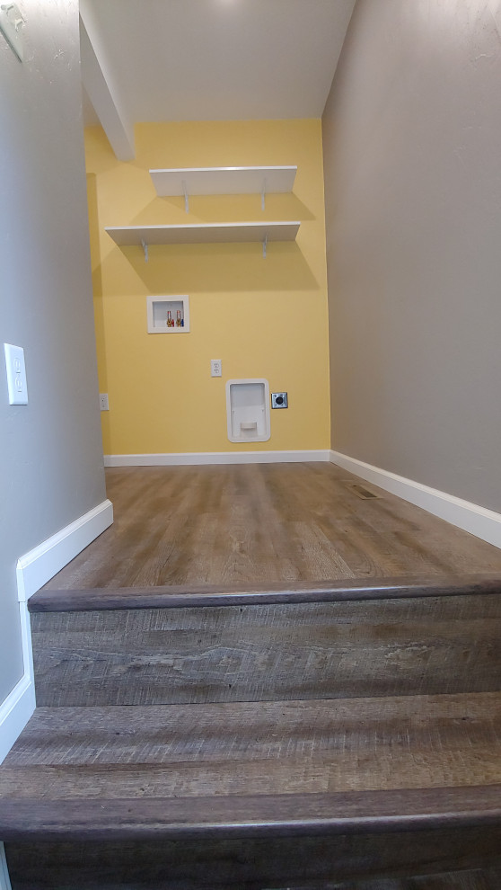This is an example of a small country single-wall utility room in Other with yellow walls, vinyl floors, a side-by-side washer and dryer and brown floor.