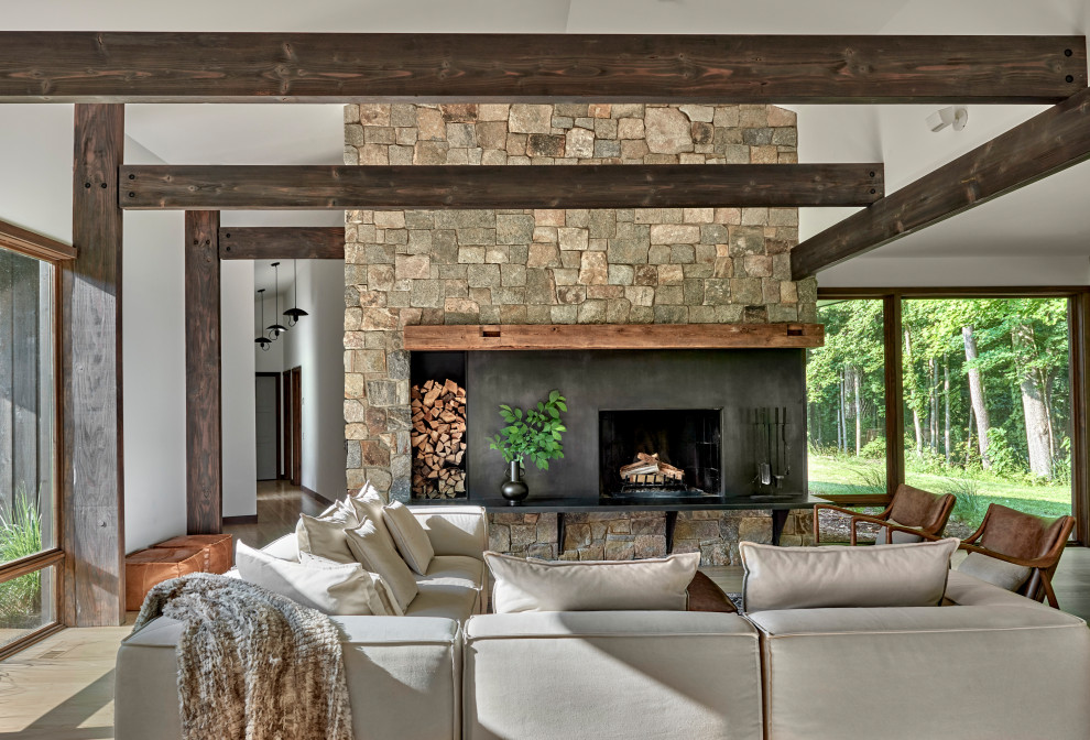 Aménagement d'un salon montagne ouvert avec un mur blanc, parquet clair, une cheminée standard, un sol beige, poutres apparentes et un manteau de cheminée en métal.