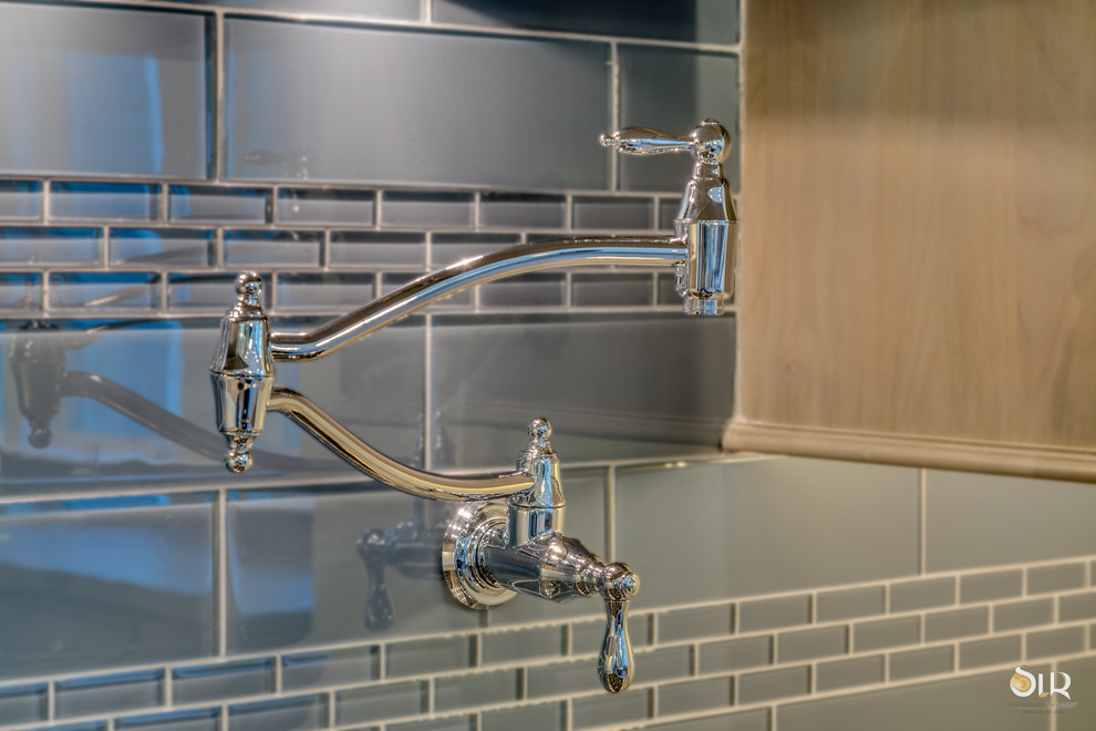 Transitional l-shaped medium tone wood floor and brown floor enclosed kitchen photo with an undermount sink, raised-panel cabinets, distressed cabinets, soapstone countertops, gray backsplash, subway tile backsplash, stainless steel appliances and an island