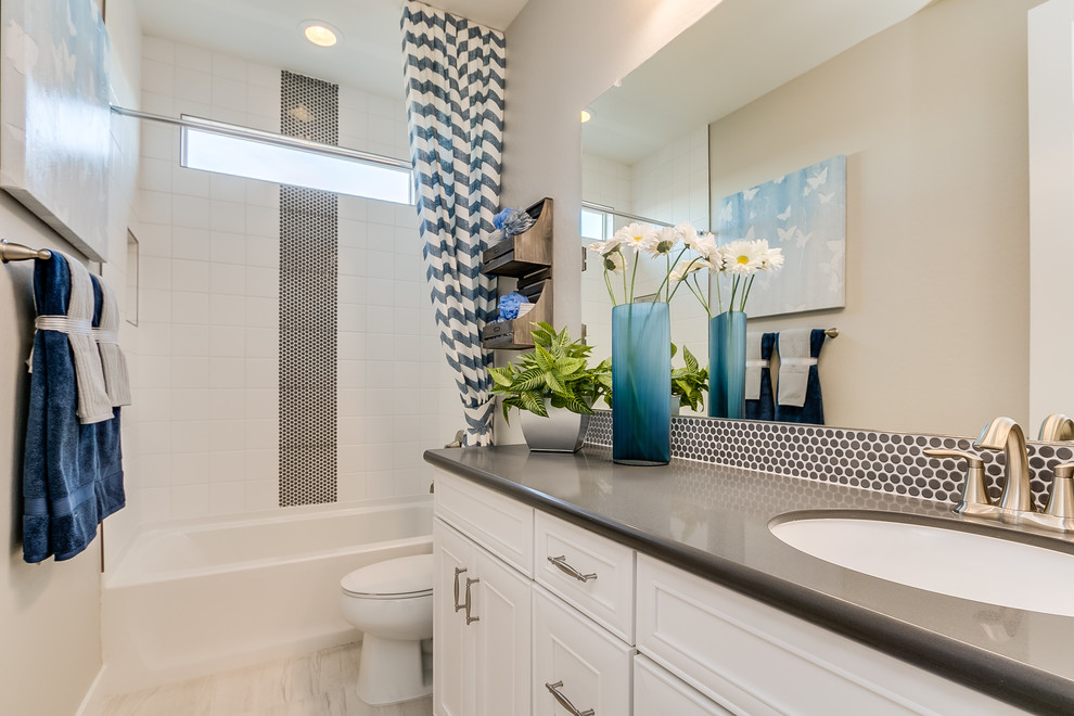 Inspiration for a mid-sized contemporary kids bathroom in Phoenix with recessed-panel cabinets, white cabinets, an alcove tub, a shower/bathtub combo, black and white tile, ceramic tile, grey walls, ceramic floors, an undermount sink, solid surface benchtops, beige floor and a shower curtain.