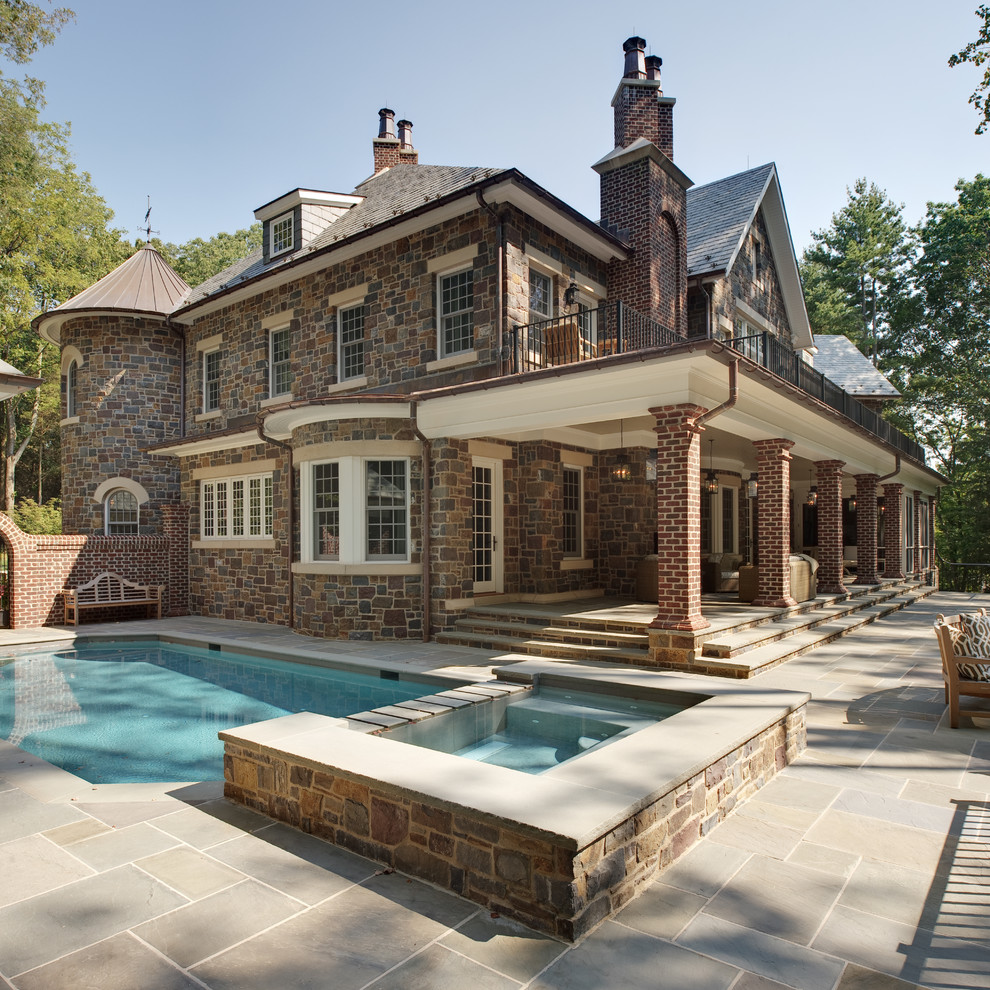 Large traditional three-storey brown exterior in New York with a gable roof and stone veneer.