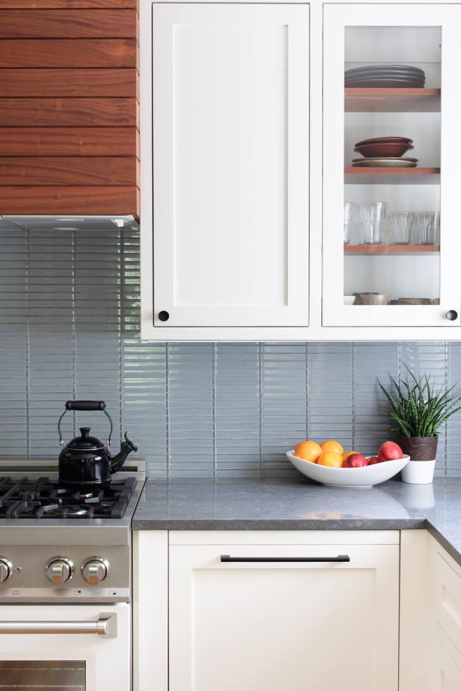 Example of a mid-sized transitional u-shaped light wood floor and brown floor eat-in kitchen design in Austin with an undermount sink, shaker cabinets, white cabinets, quartz countertops, blue backsplash, glass tile backsplash, stainless steel appliances, no island and gray countertops