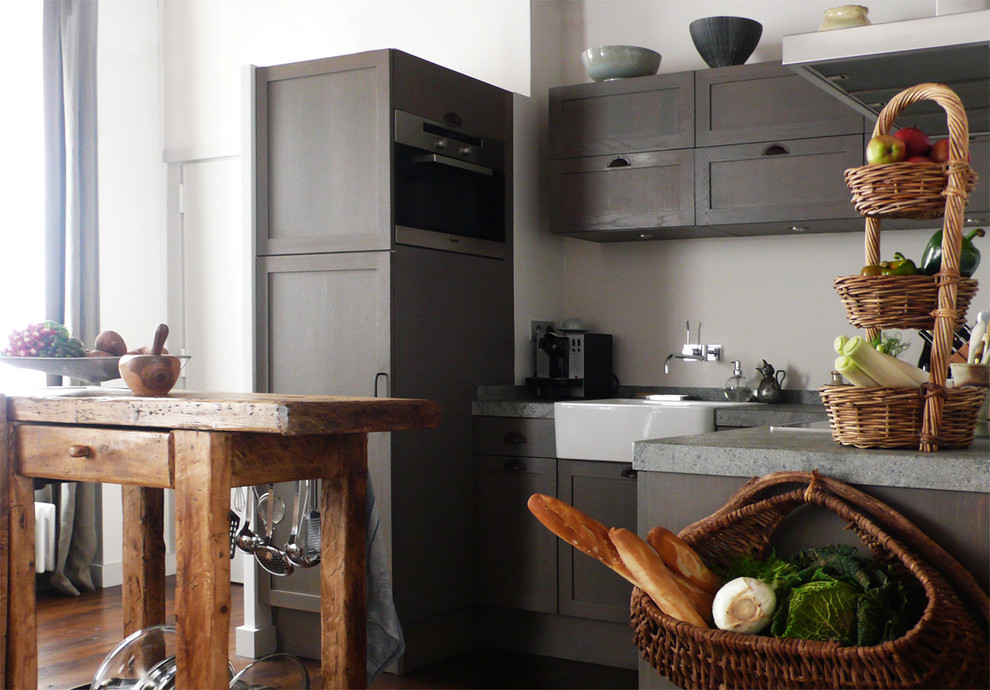 This is an example of a large contemporary u-shaped eat-in kitchen in Paris with a farmhouse sink, distressed cabinets, panelled appliances, dark hardwood floors, with island and grey splashback.