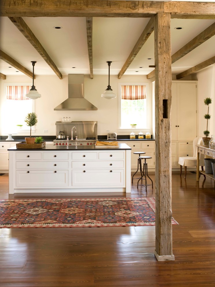 This is an example of a mid-sized country eat-in kitchen in New York with shaker cabinets, white cabinets, stainless steel appliances, dark hardwood floors and with island.