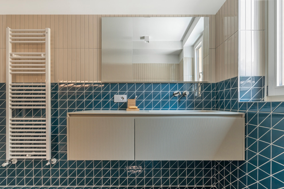 Photo of a mid-sized contemporary 3/4 bathroom in Other with flat-panel cabinets, light wood cabinets, a curbless shower, a wall-mount toilet, blue tile, ceramic tile, ceramic floors, a vessel sink, laminate benchtops, blue floor, a hinged shower door, beige benchtops, a single vanity and a floating vanity.