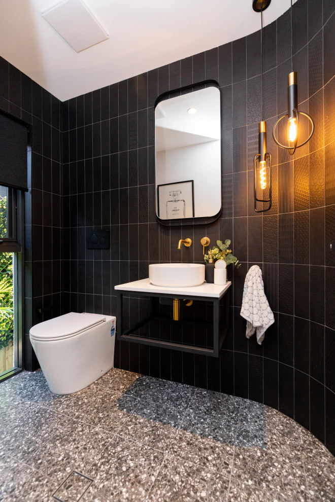 Small contemporary powder room in Sydney with black cabinets, black tile, porcelain tile, white walls, terrazzo floors, a vessel sink, engineered quartz benchtops, black floor, white benchtops and a floating vanity.