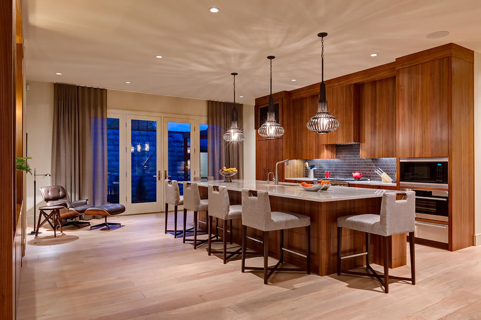 Example of a trendy single-wall kitchen design in Calgary with an undermount sink, flat-panel cabinets, medium tone wood cabinets, blue backsplash, stainless steel appliances and an island