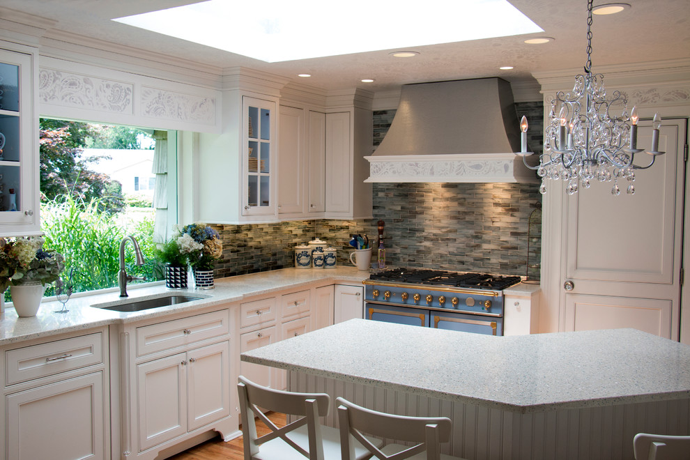 This is an example of a mid-sized traditional l-shaped separate kitchen in New York with an undermount sink, beaded inset cabinets, white cabinets, recycled glass benchtops, blue splashback, glass tile splashback, panelled appliances, light hardwood floors, with island and brown floor.