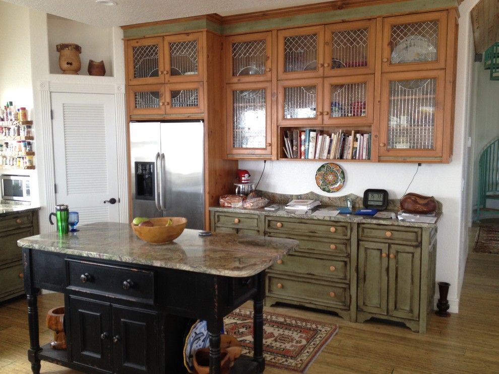 Inspiration for a mid-sized tropical l-shaped eat-in kitchen in Orlando with recessed-panel cabinets, distressed cabinets, granite benchtops, stainless steel appliances, medium hardwood floors and with island.