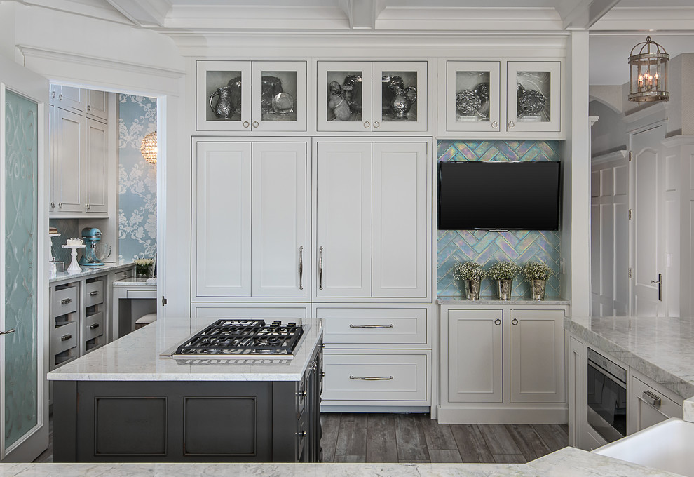 Inspiration for a mid-sized transitional u-shaped eat-in kitchen in Detroit with a farmhouse sink, flat-panel cabinets, white cabinets, solid surface benchtops, blue splashback, subway tile splashback, panelled appliances, medium hardwood floors, multiple islands, grey floor and white benchtop.