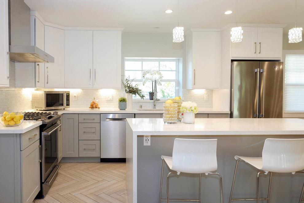 Inspiration for a large contemporary l-shaped eat-in kitchen in Los Angeles with a drop-in sink, shaker cabinets, white cabinets, quartz benchtops, multi-coloured splashback, ceramic splashback, stainless steel appliances, porcelain floors, with island, beige floor and white benchtop.