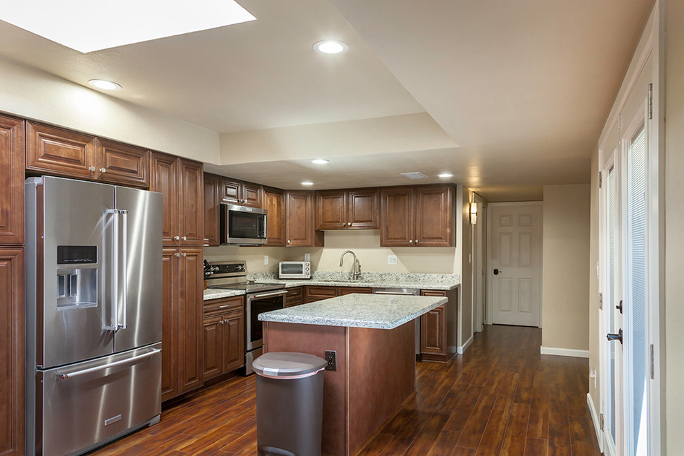 Enclosed kitchen - mid-sized transitional l-shaped laminate floor and brown floor enclosed kitchen idea in Phoenix with an undermount sink, shaker cabinets, medium tone wood cabinets, granite countertops, multicolored backsplash, stone slab backsplash, stainless steel appliances and an island