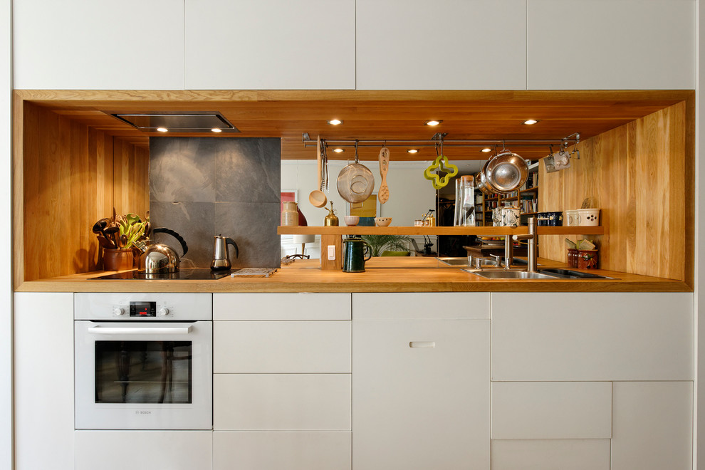 Mid-sized contemporary single-wall kitchen in Paris with a single-bowl sink, beaded inset cabinets, beige cabinets, wood benchtops, beige splashback, timber splashback, stainless steel appliances and multiple islands.