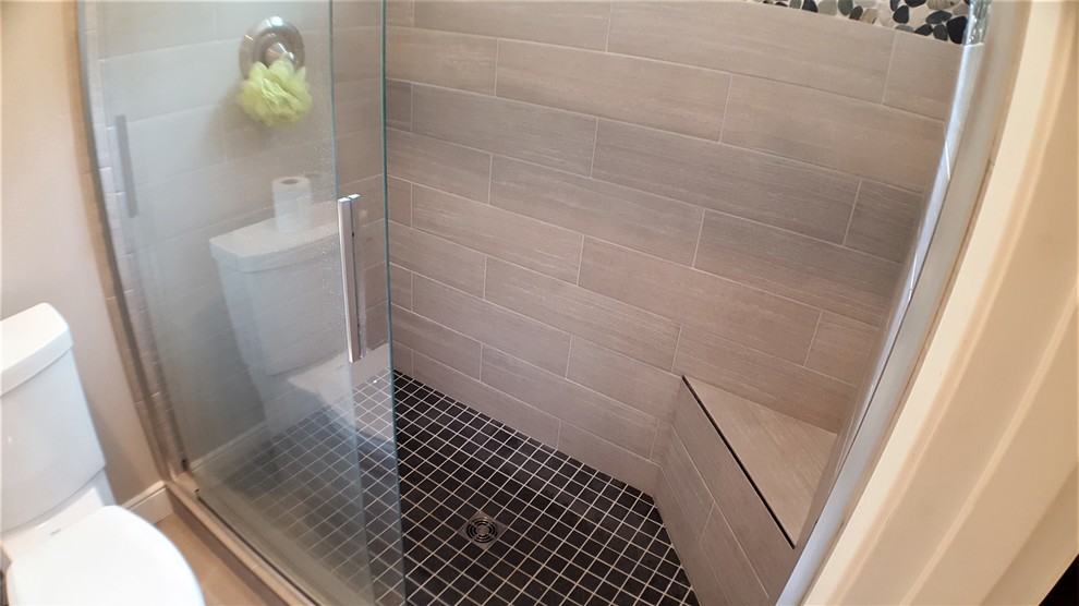 This is an example of a mid-sized transitional master bathroom in Seattle with shaker cabinets, dark wood cabinets, an alcove shower, a one-piece toilet, gray tile, porcelain tile, grey walls, porcelain floors, an undermount sink, engineered quartz benchtops, grey floor and a sliding shower screen.