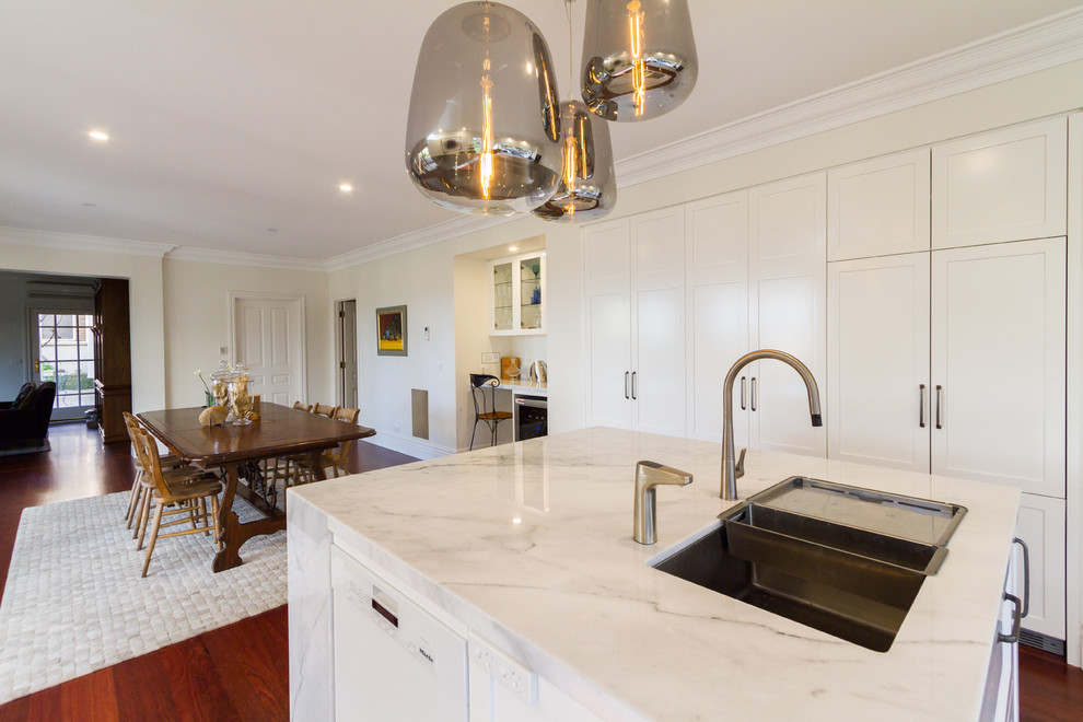 Inspiration for a large contemporary u-shaped eat-in kitchen in Melbourne with an undermount sink, shaker cabinets, white cabinets, marble benchtops, white splashback, window splashback, black appliances, dark hardwood floors, with island, brown floor and white benchtop.