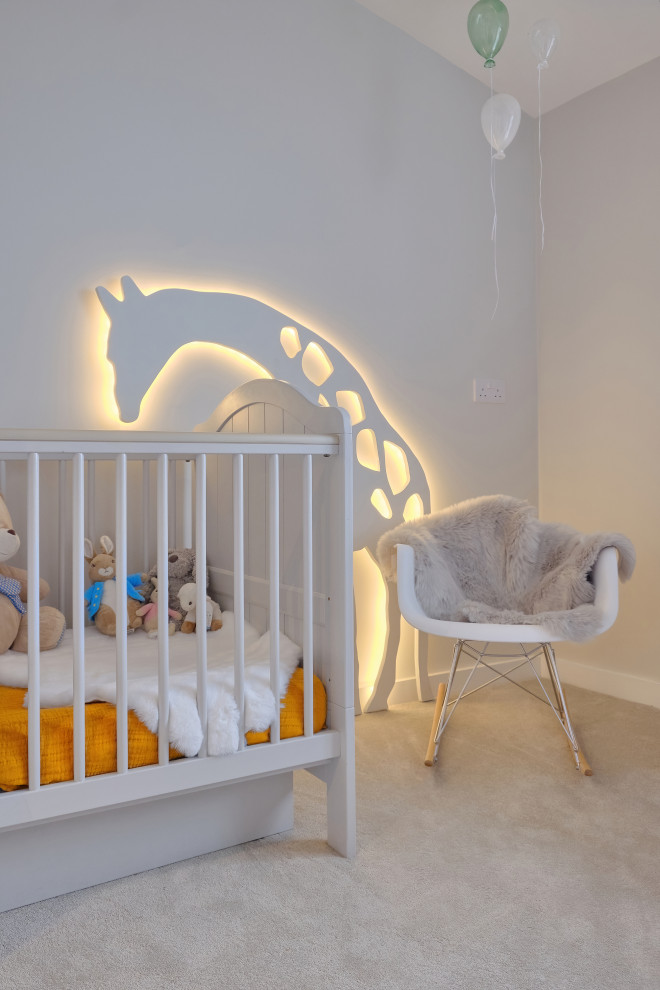 Cette image montre une petite chambre de bébé neutre design avec un mur gris et sol en stratifié.