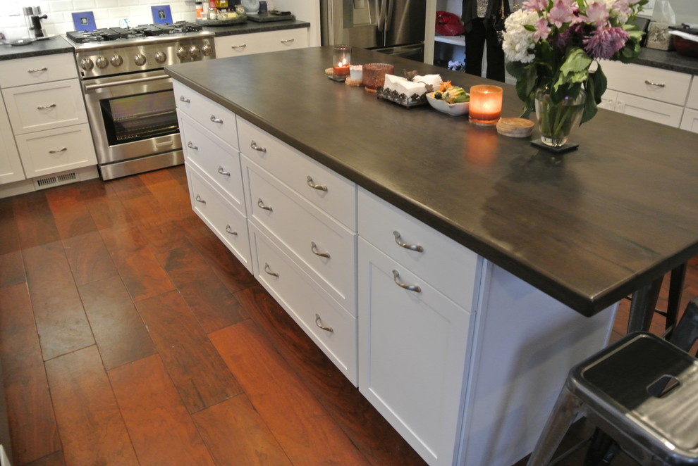 Inspiration for a transitional medium tone wood floor kitchen remodel in Boston with shaker cabinets, white cabinets, granite countertops, white backsplash, subway tile backsplash, stainless steel appliances and an island