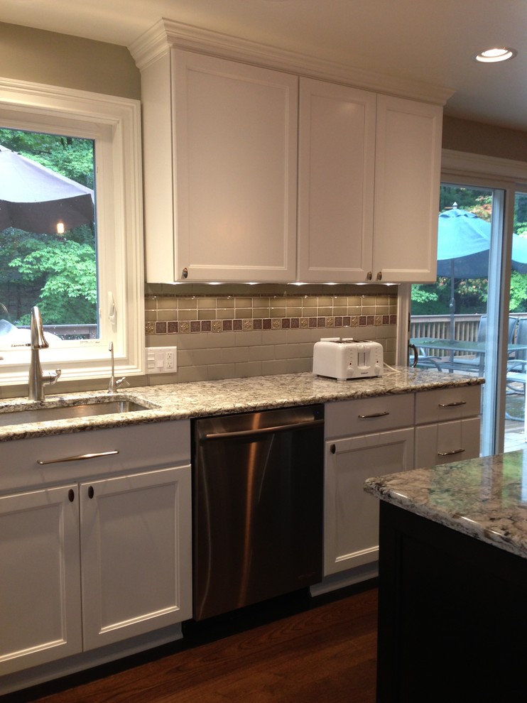 Photo of a mid-sized transitional l-shaped eat-in kitchen in Cleveland with white cabinets, granite benchtops, stainless steel appliances, with island, an undermount sink, recessed-panel cabinets, medium hardwood floors and multi-coloured splashback.