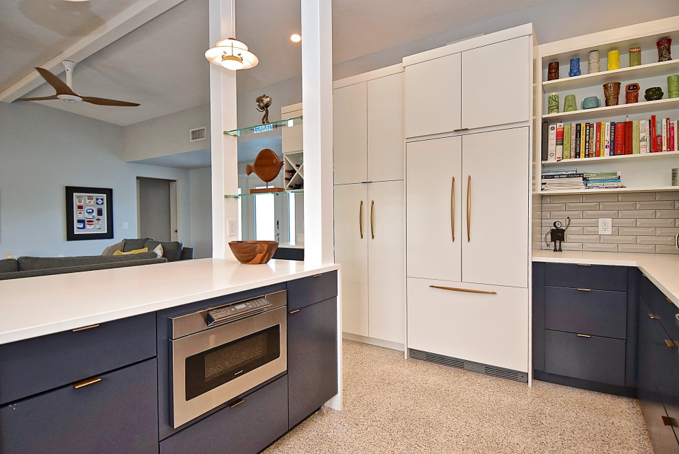 Photo of a large midcentury u-shaped kitchen in Tampa with a single-bowl sink, flat-panel cabinets, blue cabinets, quartz benchtops, grey splashback, ceramic splashback, stainless steel appliances, terrazzo floors, with island and white benchtop.