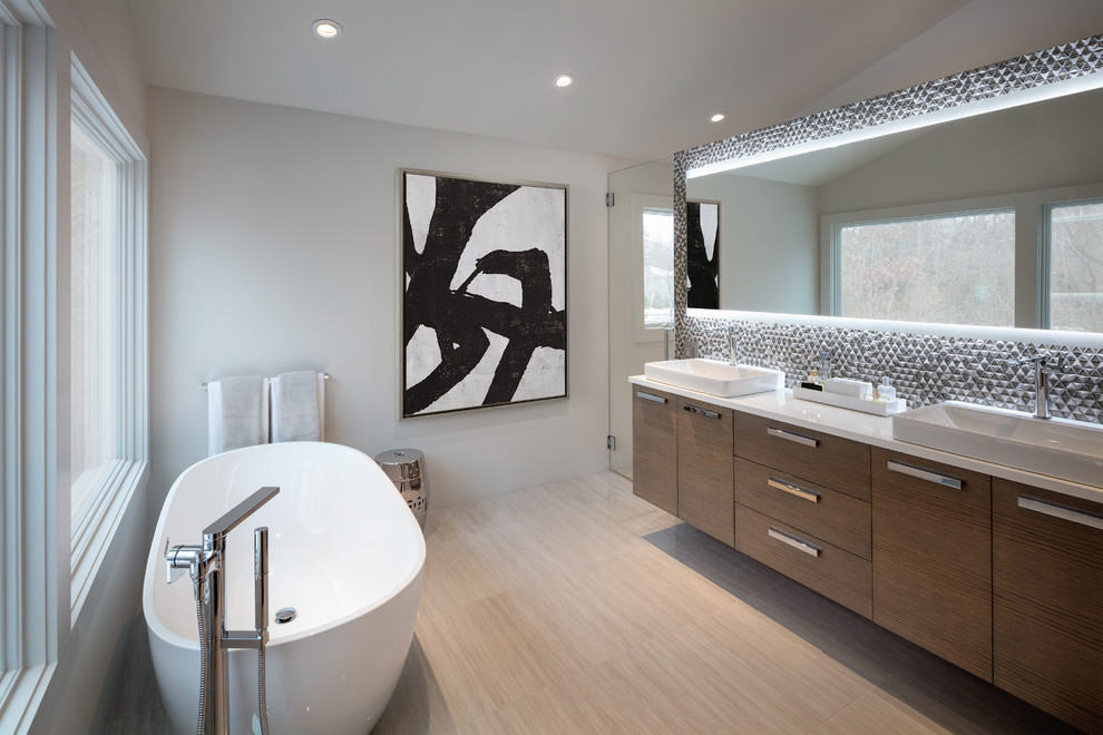 Photo of a contemporary master bathroom in New York with flat-panel cabinets, medium wood cabinets, a freestanding tub, a corner shower, gray tile, white walls, a vessel sink, beige floor and a hinged shower door.