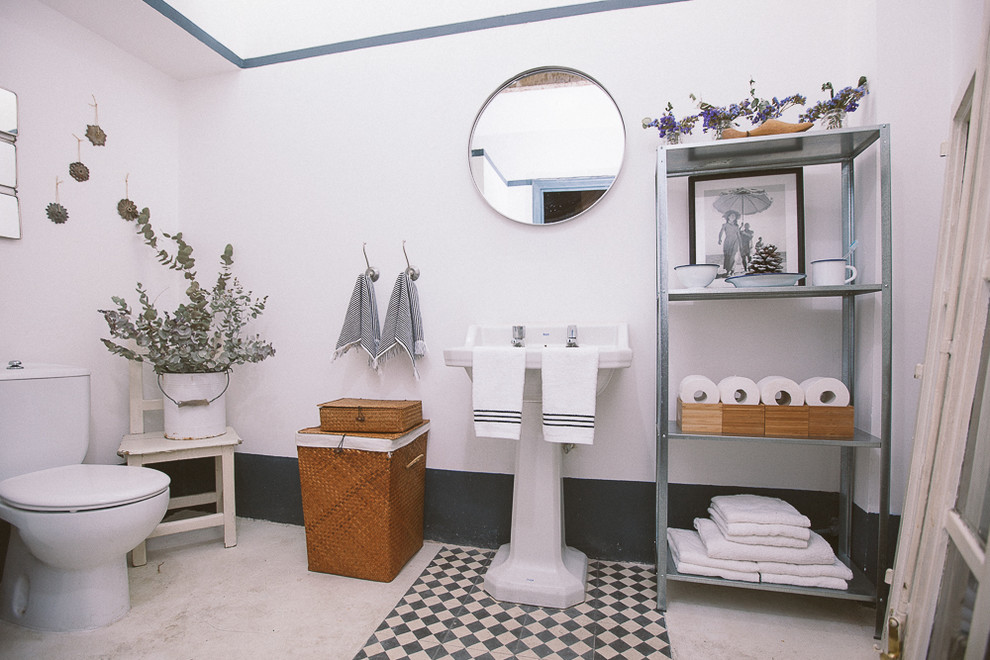 Mid-sized mediterranean powder room in Madrid with a two-piece toilet, white walls, a pedestal sink and furniture-like cabinets.