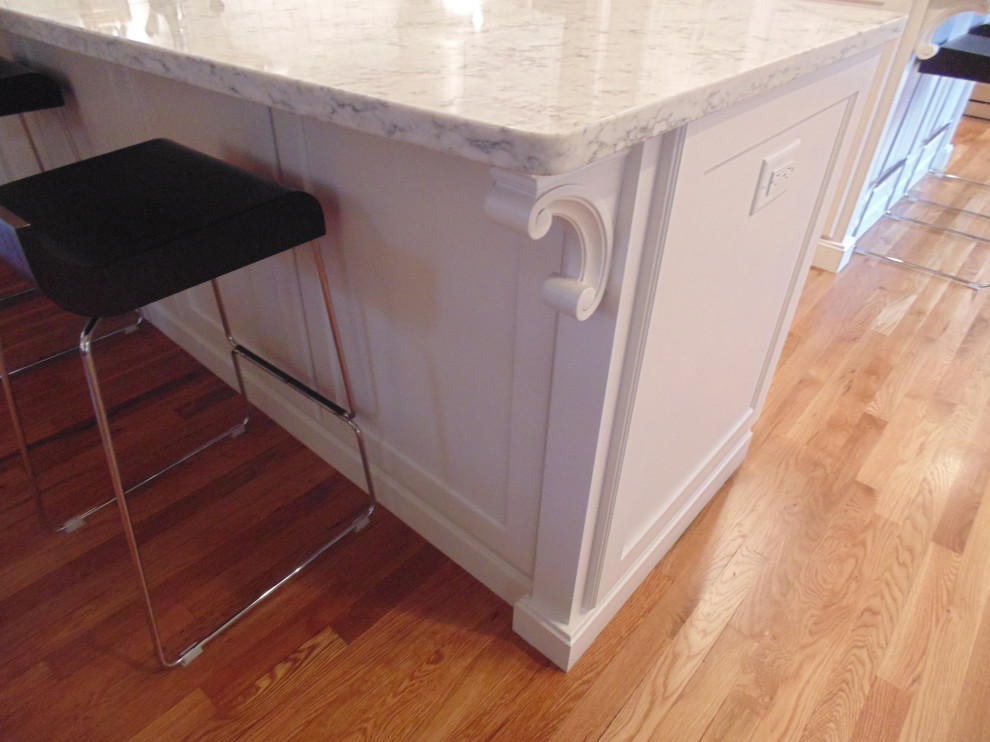 Example of a large transitional u-shaped medium tone wood floor and brown floor eat-in kitchen design with an undermount sink, recessed-panel cabinets, white cabinets, quartz countertops, white backsplash, subway tile backsplash, stainless steel appliances, an island and white countertops