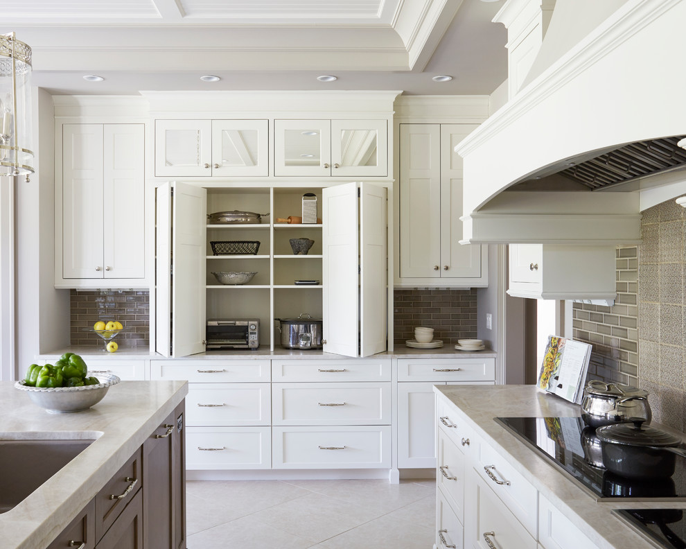 Photo of a large transitional u-shaped eat-in kitchen in Other with a double-bowl sink, raised-panel cabinets, white cabinets, marble benchtops, beige splashback, ceramic splashback, stainless steel appliances, ceramic floors, multiple islands and grey floor.