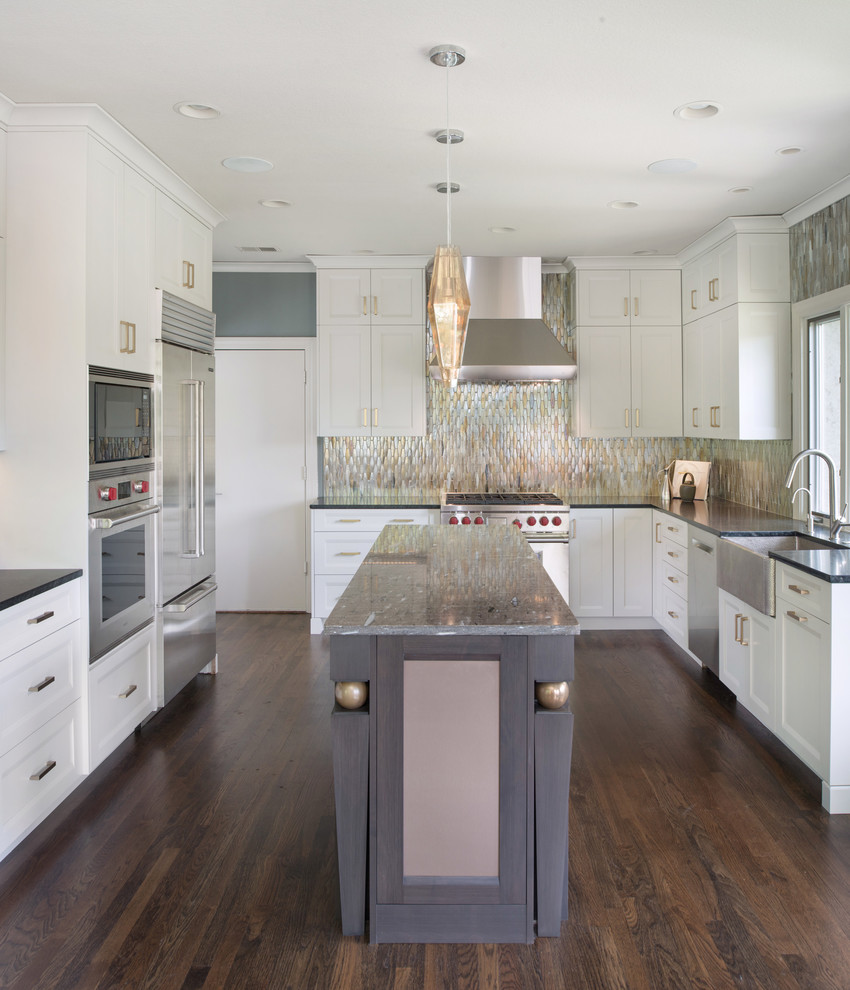 Large transitional l-shaped kitchen pantry in Kansas City with a farmhouse sink, shaker cabinets, white cabinets, metal splashback, stainless steel appliances, dark hardwood floors, with island, brown floor and metallic splashback.