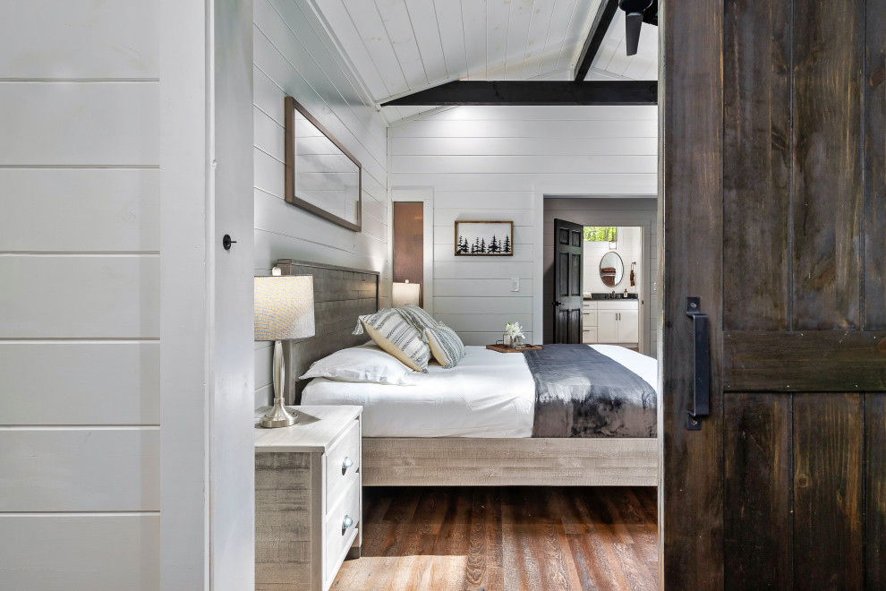 Design ideas for a large modern master bedroom in Houston with white walls, dark hardwood floors, brown floor, exposed beam and planked wall panelling.