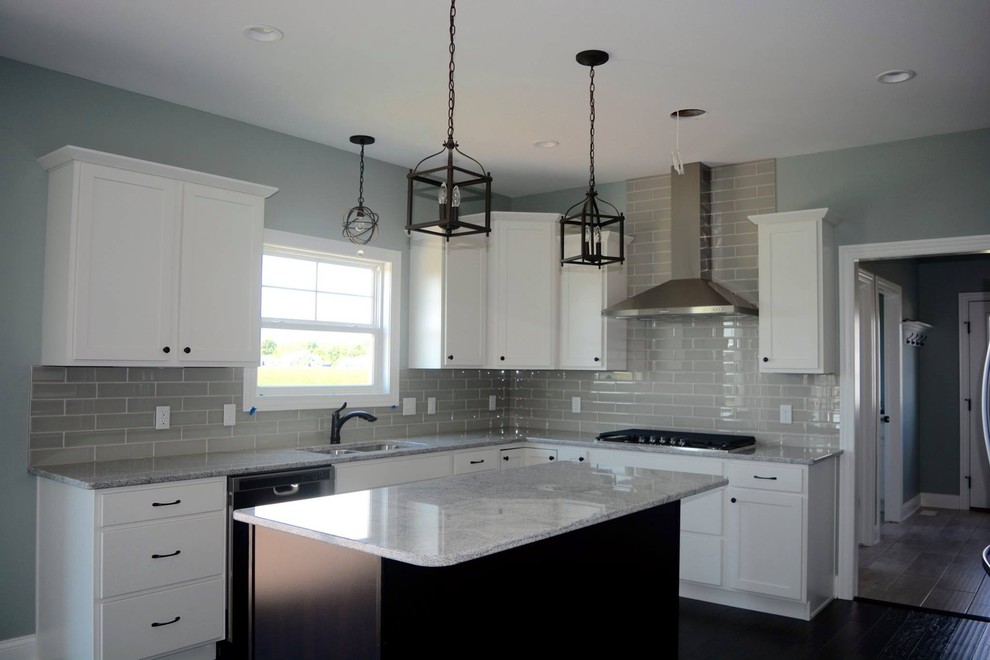 Example of a large transitional l-shaped dark wood floor open concept kitchen design with an undermount sink, shaker cabinets, white cabinets, granite countertops, gray backsplash, porcelain backsplash, stainless steel appliances and an island