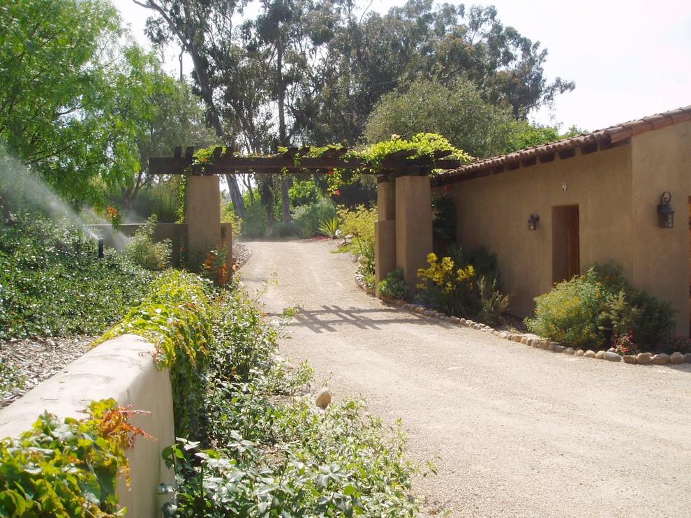 This is an example of a mediterranean front yard full sun driveway in San Diego with gravel.