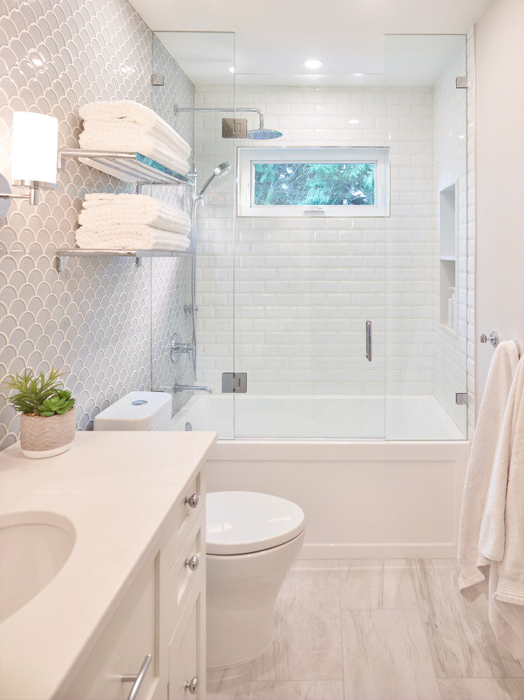 Small transitional kids bathroom in Vancouver with shaker cabinets, white cabinets, an alcove tub, a shower/bathtub combo, a one-piece toilet, gray tile, glass sheet wall, grey walls, porcelain floors, an undermount sink, engineered quartz benchtops, grey floor, a hinged shower door and white benchtops.