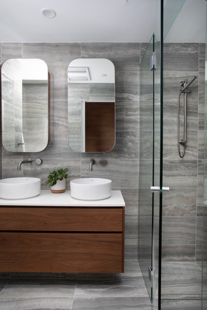 This is an example of a large contemporary 3/4 bathroom in Brisbane with medium wood cabinets, a double shower, a one-piece toilet, gray tile, porcelain tile, grey walls, porcelain floors, a vessel sink, grey floor, a hinged shower door, white benchtops, a niche, a double vanity, a floating vanity and flat-panel cabinets.
