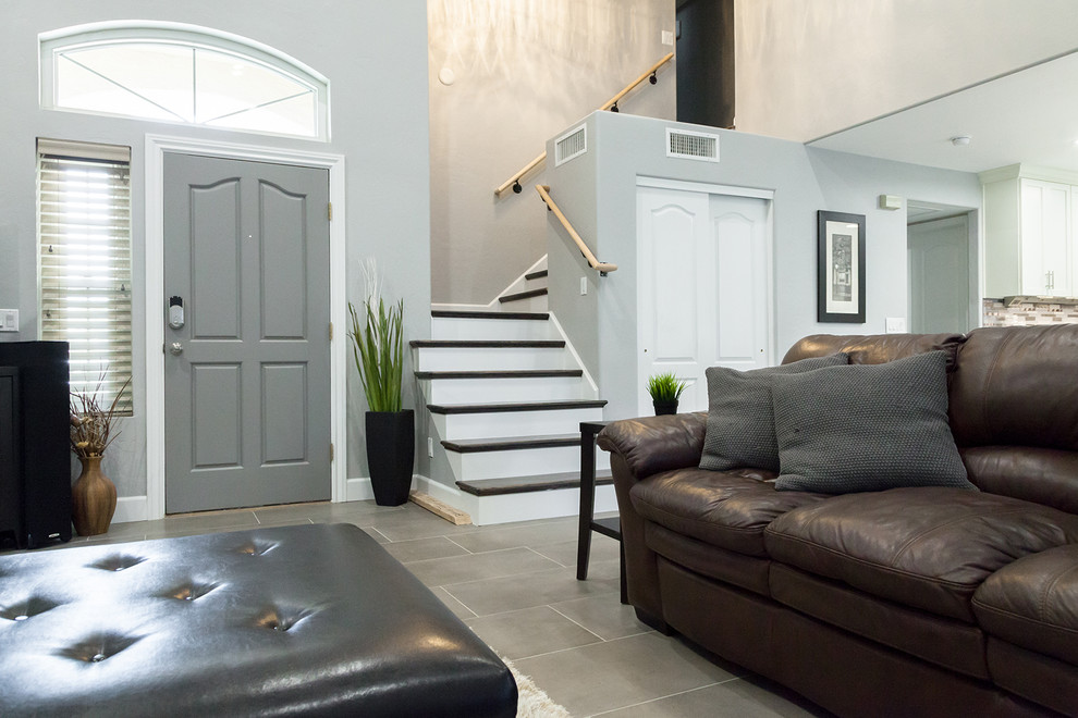Mid-sized transitional l-shaped porcelain tile and gray floor open concept kitchen photo in Phoenix with an undermount sink, shaker cabinets, white cabinets, quartz countertops, gray backsplash, glass tile backsplash, black appliances, an island and gray countertops