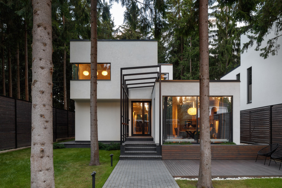На фото: двухэтажный, белый частный загородный дом среднего размера в современном стиле с облицовкой из цементной штукатурки и плоской крышей с