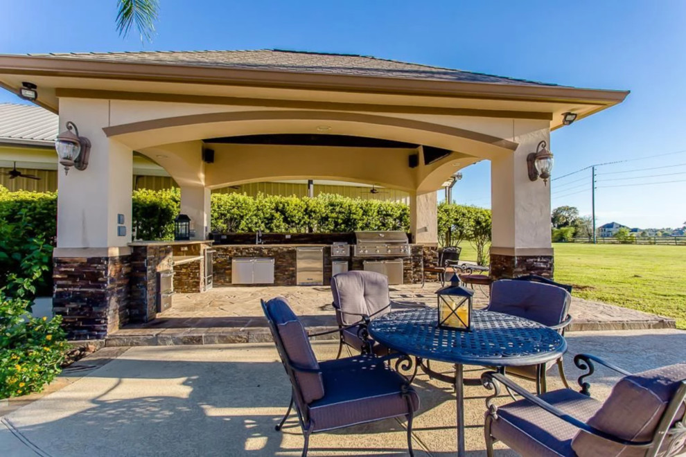 Expansive traditional backyard patio in Houston with an outdoor kitchen, natural stone pavers and a gazebo/cabana.