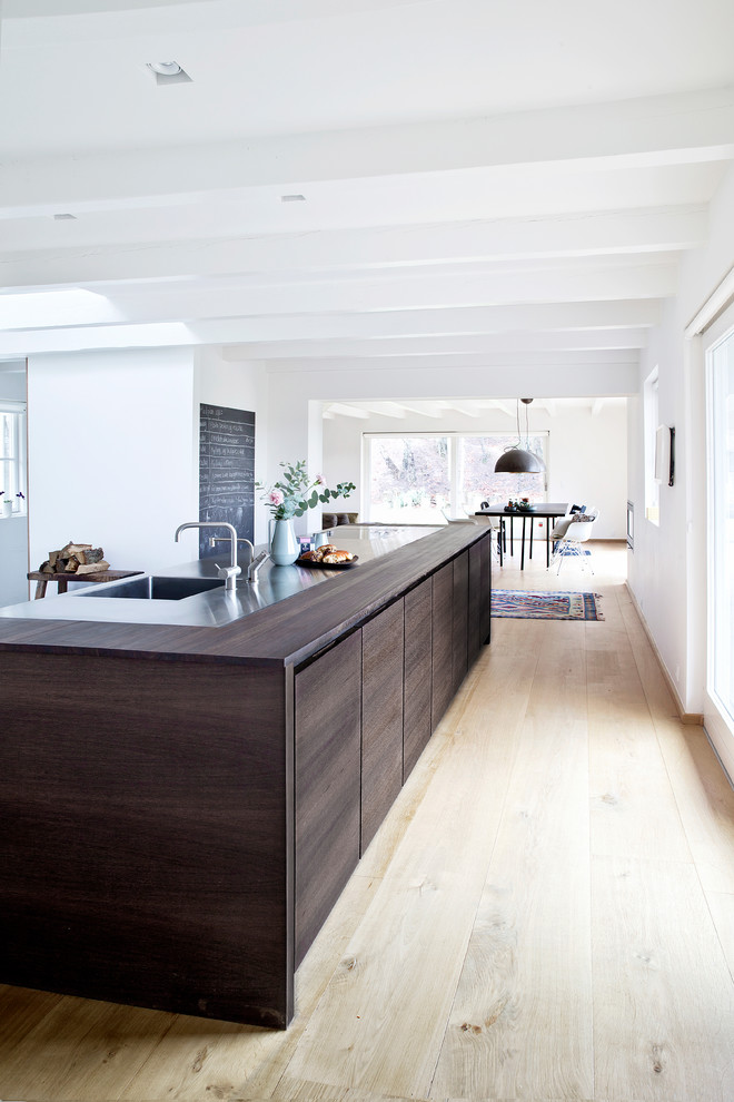 Photo of a large modern eat-in kitchen in Copenhagen with an integrated sink, flat-panel cabinets, dark wood cabinets, wood benchtops, light hardwood floors and with island.