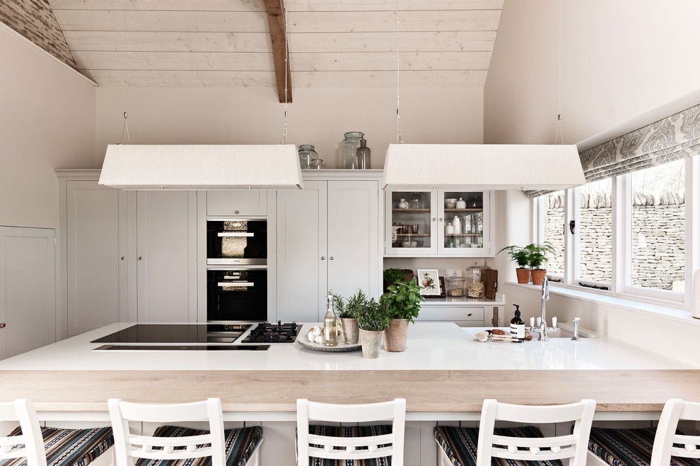 This is an example of a small country single-wall eat-in kitchen in Wiltshire with recessed-panel cabinets and white cabinets.