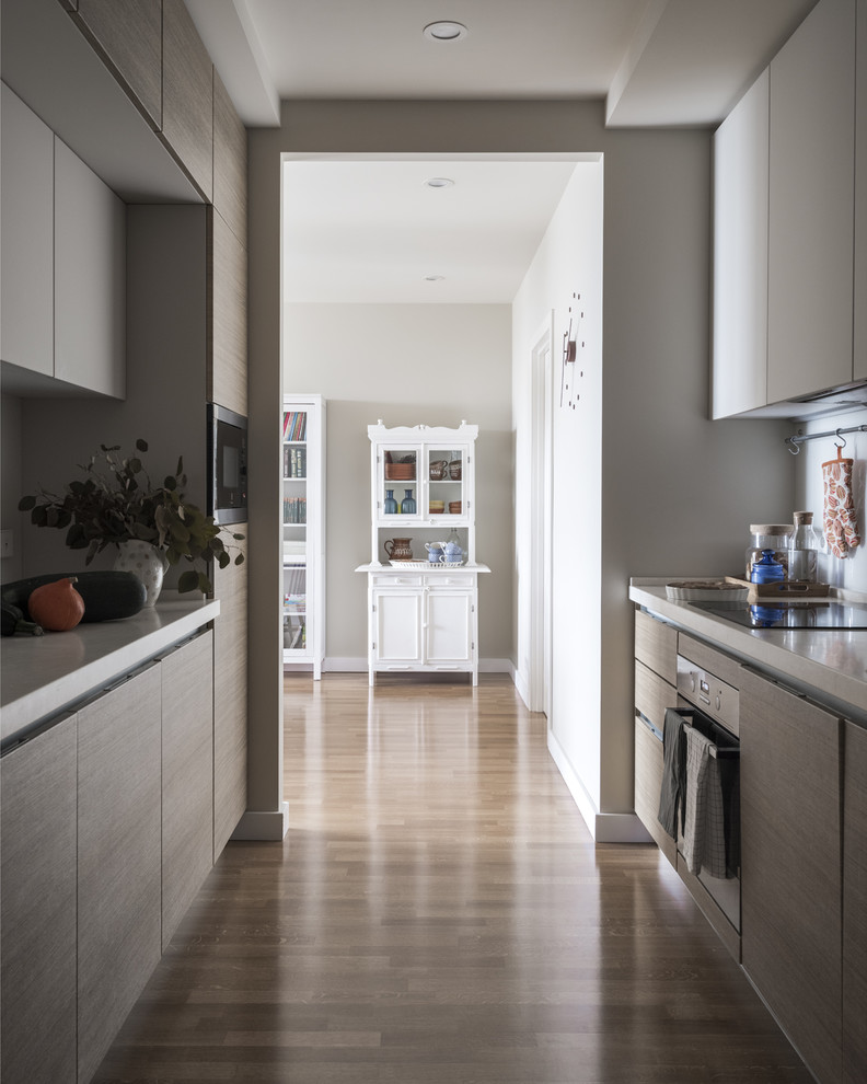 This is an example of a mid-sized scandinavian galley kitchen in Moscow with flat-panel cabinets, light wood cabinets, quartz benchtops, white splashback, glass sheet splashback, medium hardwood floors, no island, beige floor and stainless steel appliances.