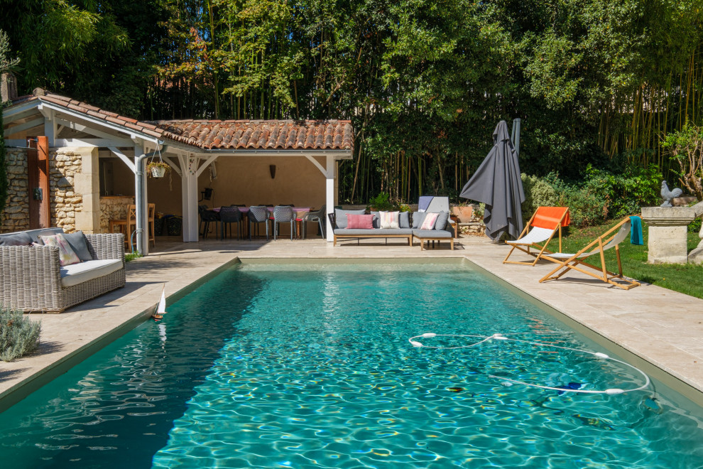 Idee per una grande piscina chic rettangolare dietro casa con paesaggistica bordo piscina e pavimentazioni in pietra naturale