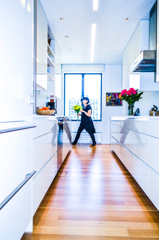 Small minimalist galley light wood floor enclosed kitchen photo in San Francisco with an undermount sink, flat-panel cabinets, white cabinets, quartz countertops, white backsplash, glass tile backsplash and stainless steel appliances