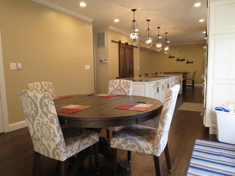 Large transitional galley dark wood floor and brown floor kitchen photo with a double-bowl sink, raised-panel cabinets, white cabinets, granite countertops, white backsplash, porcelain backsplash, stainless steel appliances and an island