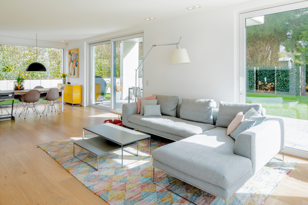 Großes, Offenes Modernes Wohnzimmer mit weißer Wandfarbe, braunem Holzboden, TV-Wand und braunem Boden in Düsseldorf