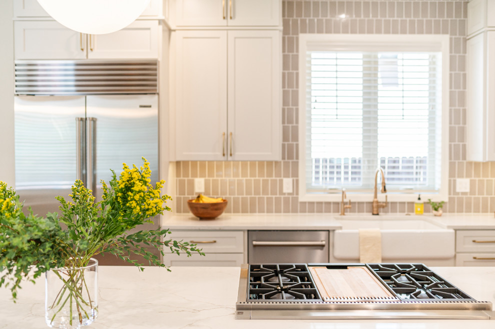 Example of a large transitional l-shaped dark wood floor and brown floor open concept kitchen design in Denver with a farmhouse sink, shaker cabinets, beige cabinets, quartz countertops, beige backsplash, ceramic backsplash, stainless steel appliances, an island and white countertops
