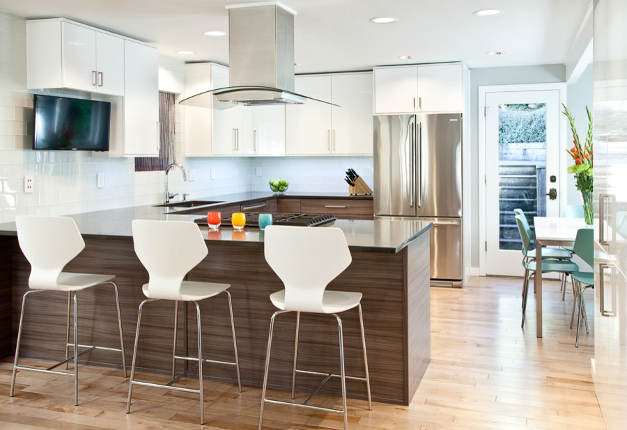 Inspiration for a mid-sized modern u-shaped eat-in kitchen in Seattle with an undermount sink, flat-panel cabinets, white cabinets, quartz benchtops, white splashback, glass tile splashback, stainless steel appliances and light hardwood floors.