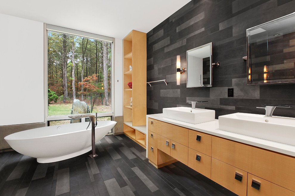 Photo of a contemporary bathroom in Portland with a freestanding tub, a vessel sink, flat-panel cabinets, gray tile and medium wood cabinets.