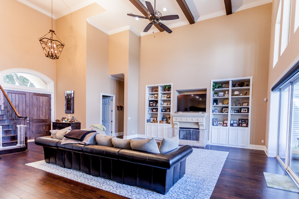 Inspiration for a large mediterranean open concept living room in Jacksonville with beige walls, medium hardwood floors, a standard fireplace and a wood fireplace surround.