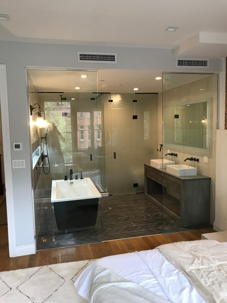 Inspiration for a large modern master wet room bathroom in Atlanta with flat-panel cabinets, grey cabinets, a freestanding tub, beige walls, a vessel sink, wood benchtops, black floor, a hinged shower door, ceramic floors and black benchtops.