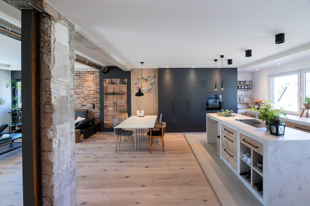 Medium sized urban galley kitchen/diner in Other with a double-bowl sink, flat-panel cabinets, black cabinets, concrete worktops, black appliances, medium hardwood flooring, beige floors and grey worktops.