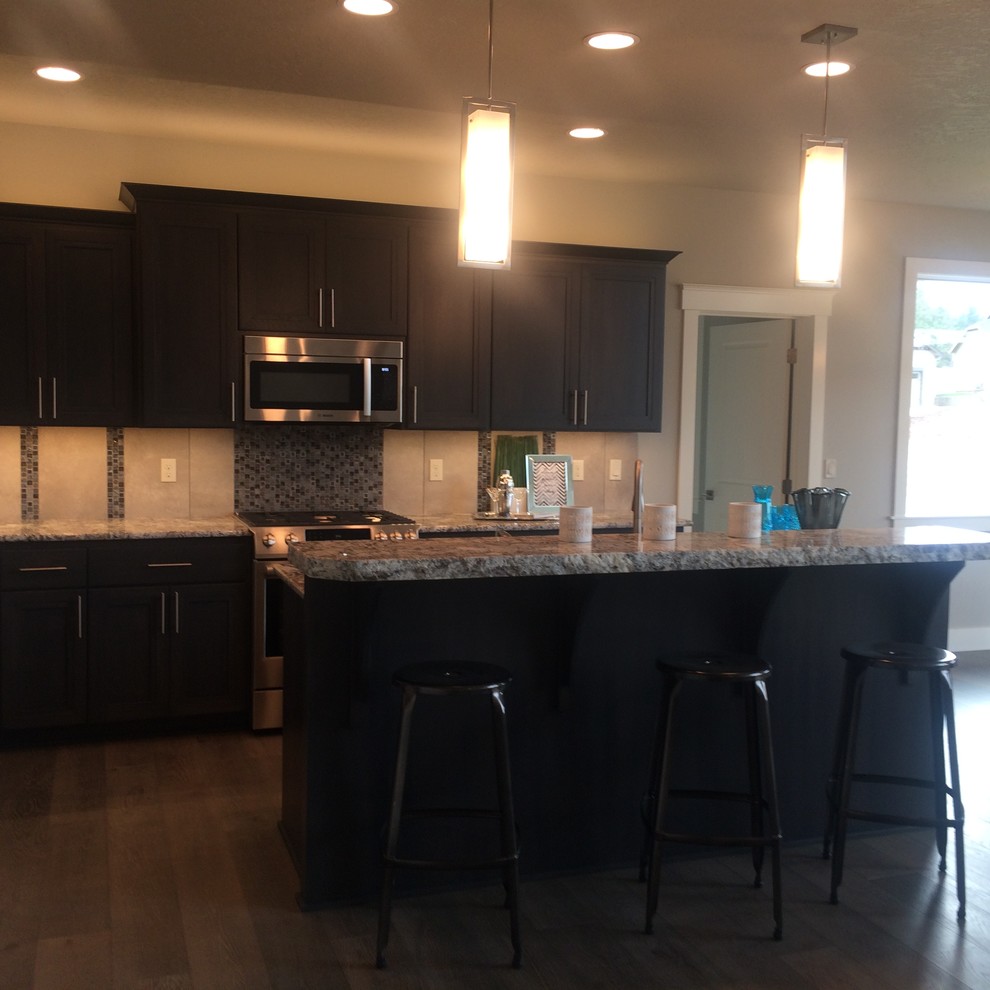 Mid-sized transitional galley dark wood floor and brown floor open concept kitchen photo in Seattle with a double-bowl sink, recessed-panel cabinets, dark wood cabinets, granite countertops, stainless steel appliances and an island